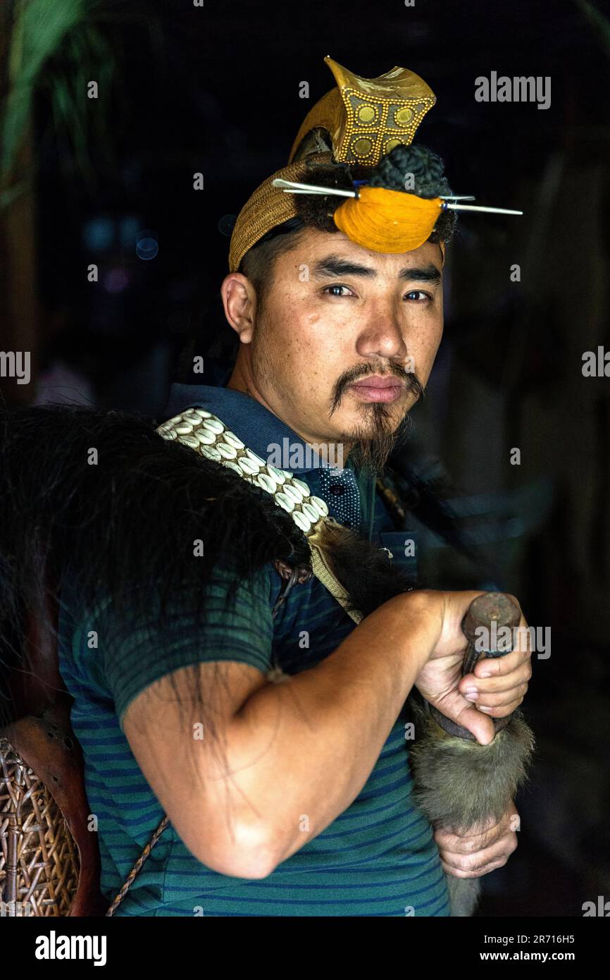 Ritratto di un uomo Nyishi nei suoi abiti tribali tradizionali con cappello di piuma di orna cerimoniale sulla sua testa e una spada, Arunachal Pradesh, India Foto Stock