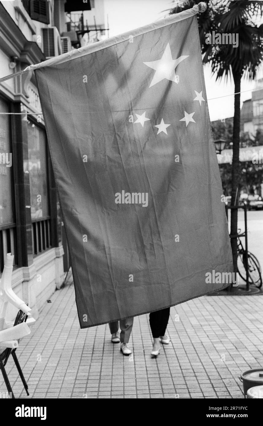 Shanghai Cina 2000. La bandiera cinese vola durante la Giornata Nazionale da centinaia di edifici in tutta Shanghai. E 'stato un residente di Shanghai, Zeng Liangsong, che ha prodotto il design vincente per la bandiera nazionale Chinas in un concorso nel 1949. La grande stella rappresenta il Partito Comunista e le quattro stelle più piccole sono le quattro classi definite originariamente da Mao Zedung: Operai, contadini, piccola borghesia e capitalisti patriottici. Zheng viveva ancora a Shanghai nel 2000, all'età di 83 anni. 2000s OMERO SYKES Foto Stock