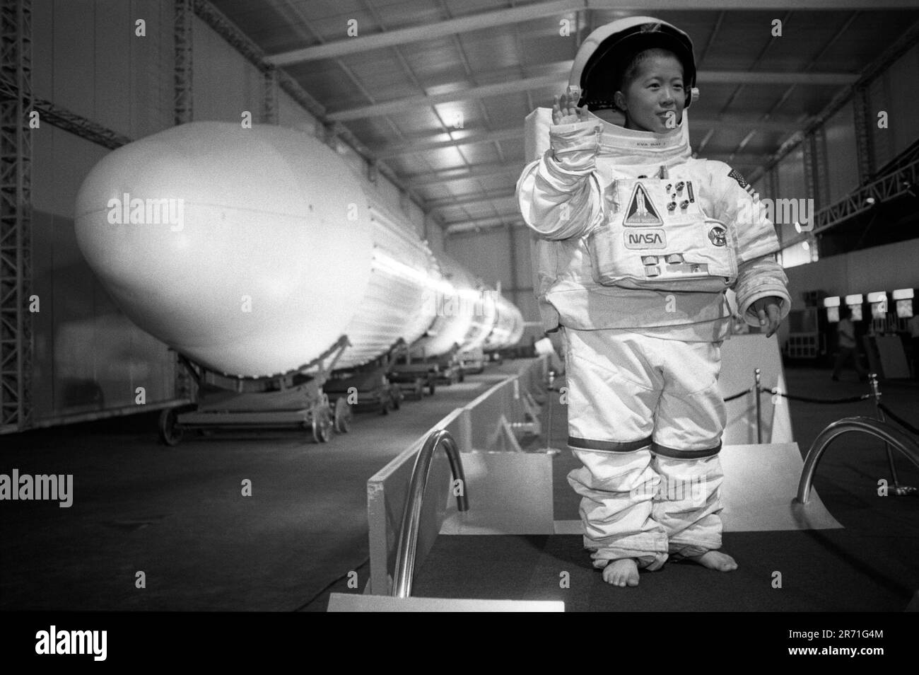 Shanghai Cina 2000. Un bambino che indossa una tuta spaziale della NASA oversize mentre viene fotografato accanto al razzo cinese 'Long March Number 3', alla mostra sul razzo del Parco Zhongshan. Shanghai, Repubblica popolare Cinese. 2000s OMERO SYKES Foto Stock