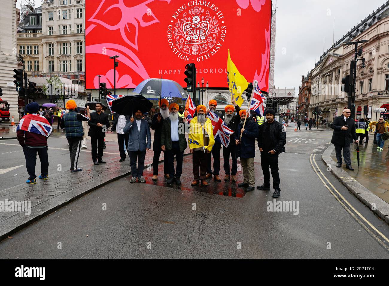 Inghilterra, Londra, Piccadilly Circus, famiglia Sikh che celebra l'incoronazione di Re Carlo III in una piovosa giornata del 6th 2023 maggio. Foto Stock