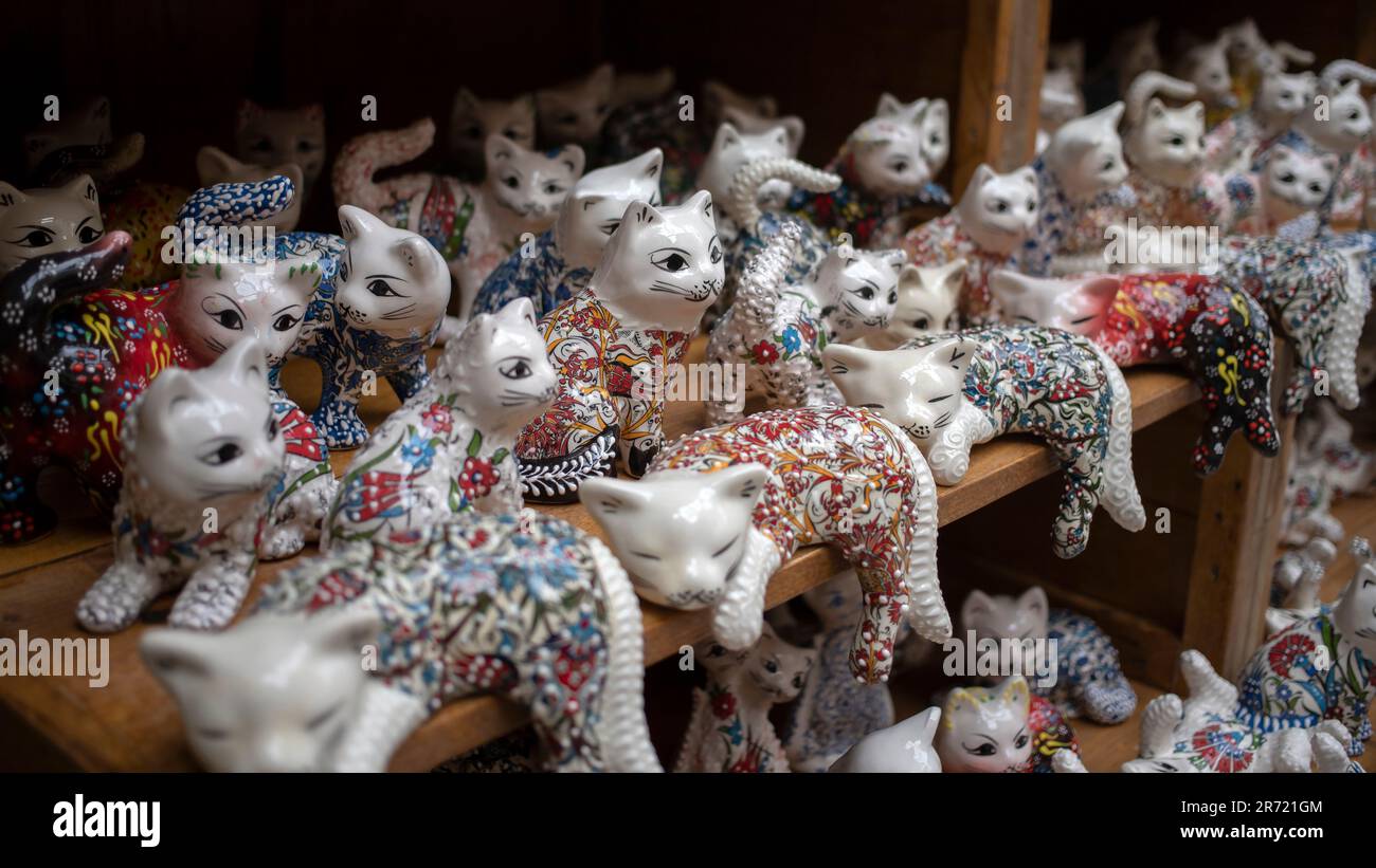 Un sacco di statuette di gatto in porcellana allineate su uno scaffale in un negozio di articoli da regalo Foto Stock