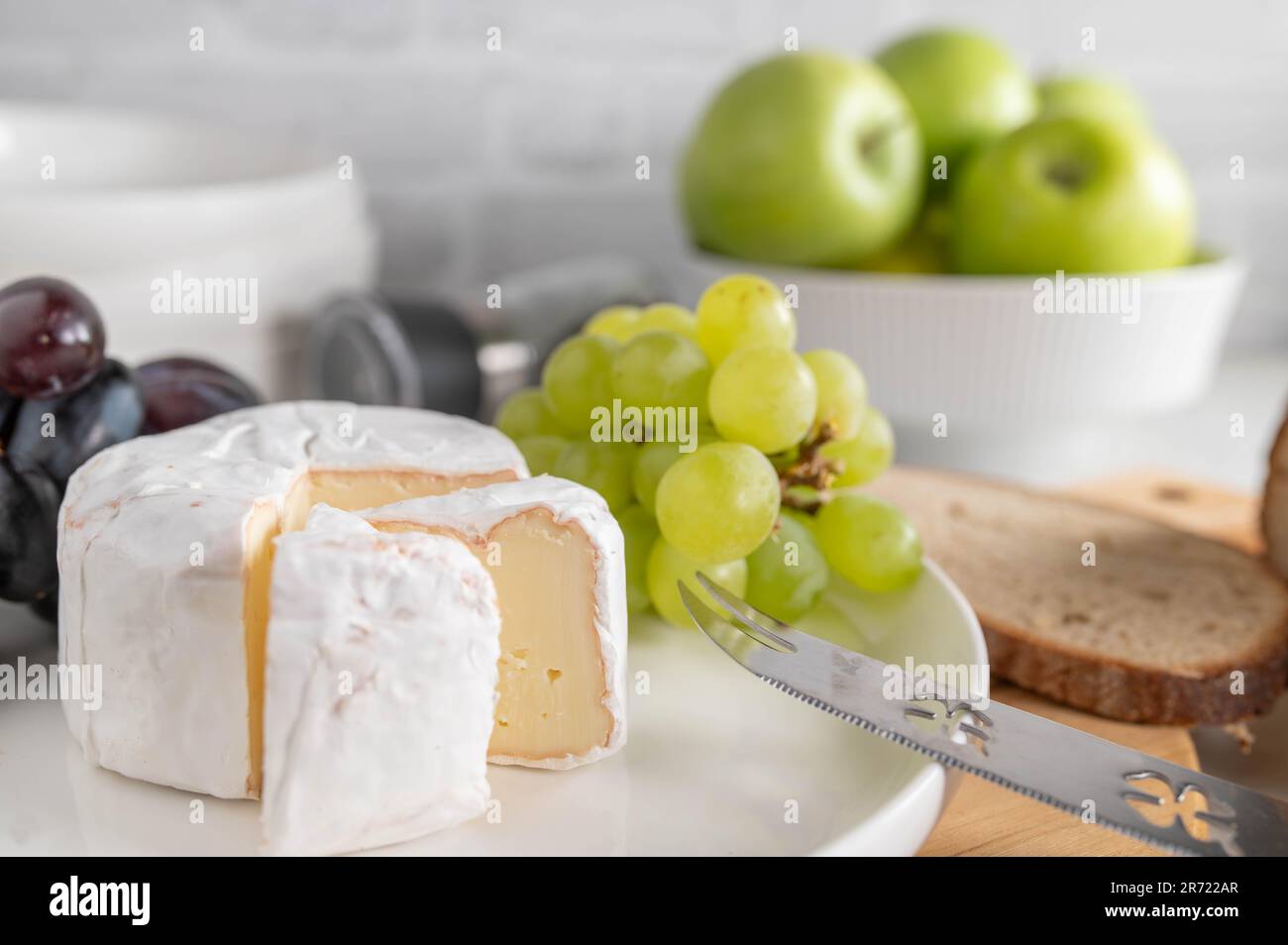 Formaggio morbido o brie e uva su un piatto bianco con pane Foto Stock