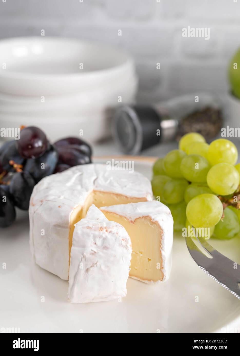 Formaggio morbido o brie e uva su un piatto bianco con pane Foto Stock