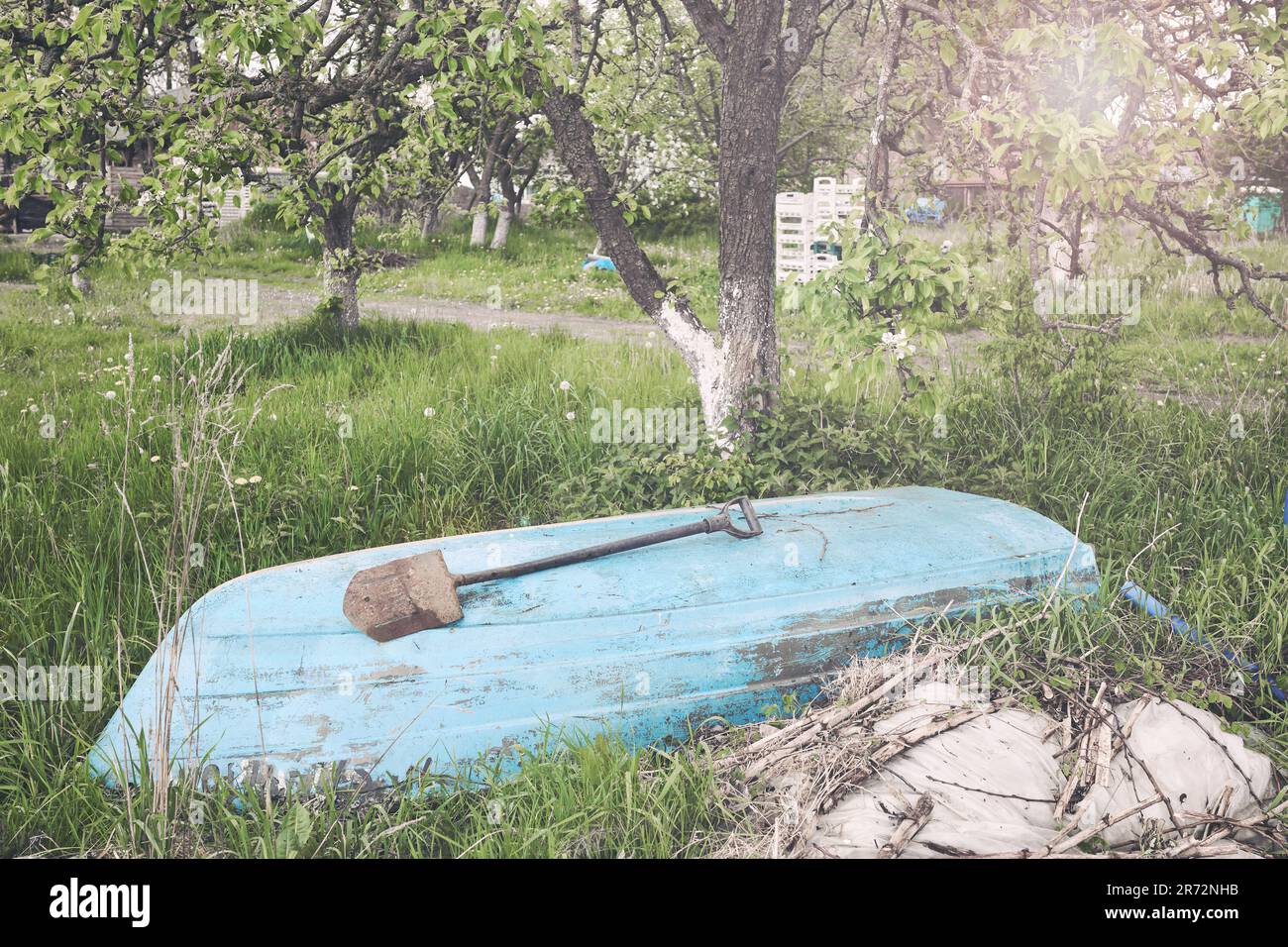 Una vecchia barca scartata sotto un albero, messa a fuoco selettiva, tonalità di colore applicato. Foto Stock