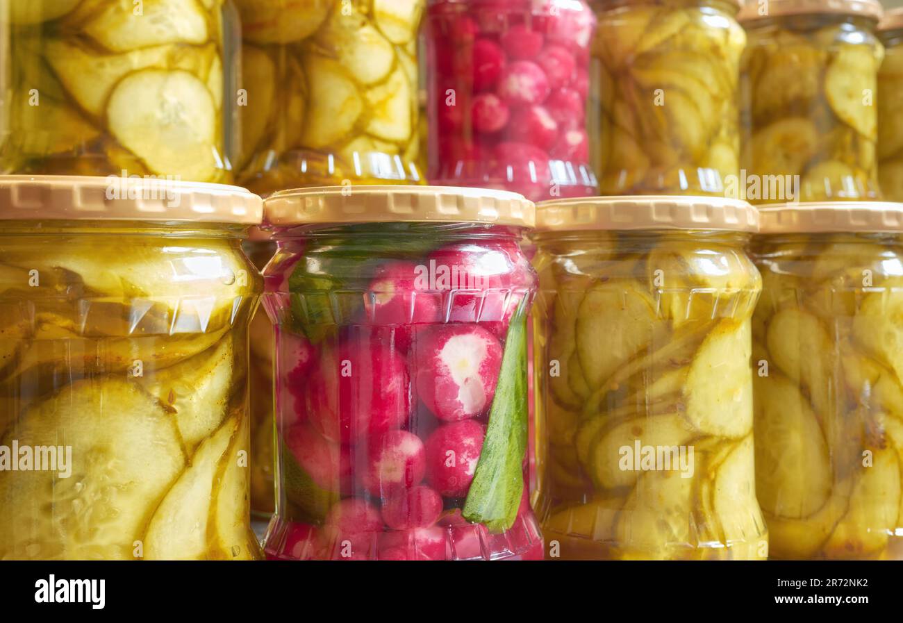Foto ravvicinata delle fette di cetriolo decapate e del ravanello in vasetti di vetro, messa a fuoco selettiva. Foto Stock