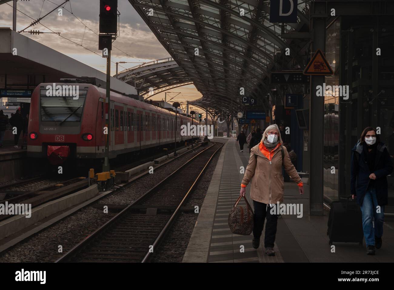 Foto delle donne che aspettano un treno sulle piattaforme della stazione ferroviaria di Koln hauptbahnhof, indossando maschere facciali durante il Coronavirus Covid 19 Health cr Foto Stock
