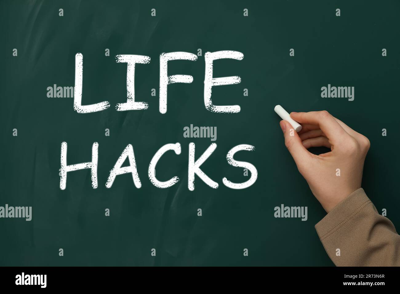 Donna che scrive parole Life Hacks sulla lavagna verde, primo piano Foto Stock