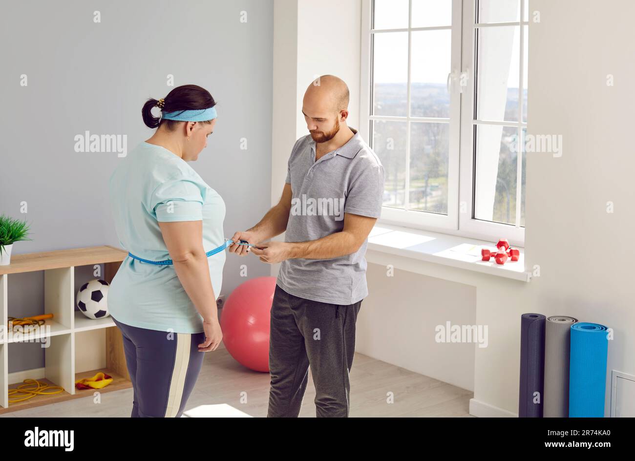 Giovane infermiera maschile misura la vita per un grassa grumo sovrappeso giovane donna dopo aver fatto esercizi sportivi. Foto Stock