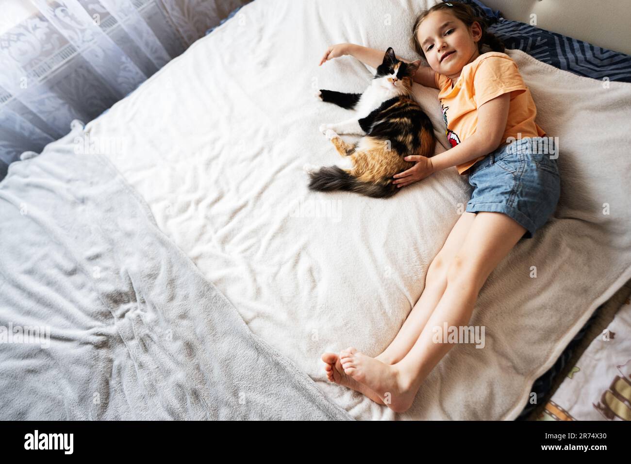 Ragazza carina che gioca con il suo gatto sul letto a casa Foto Stock