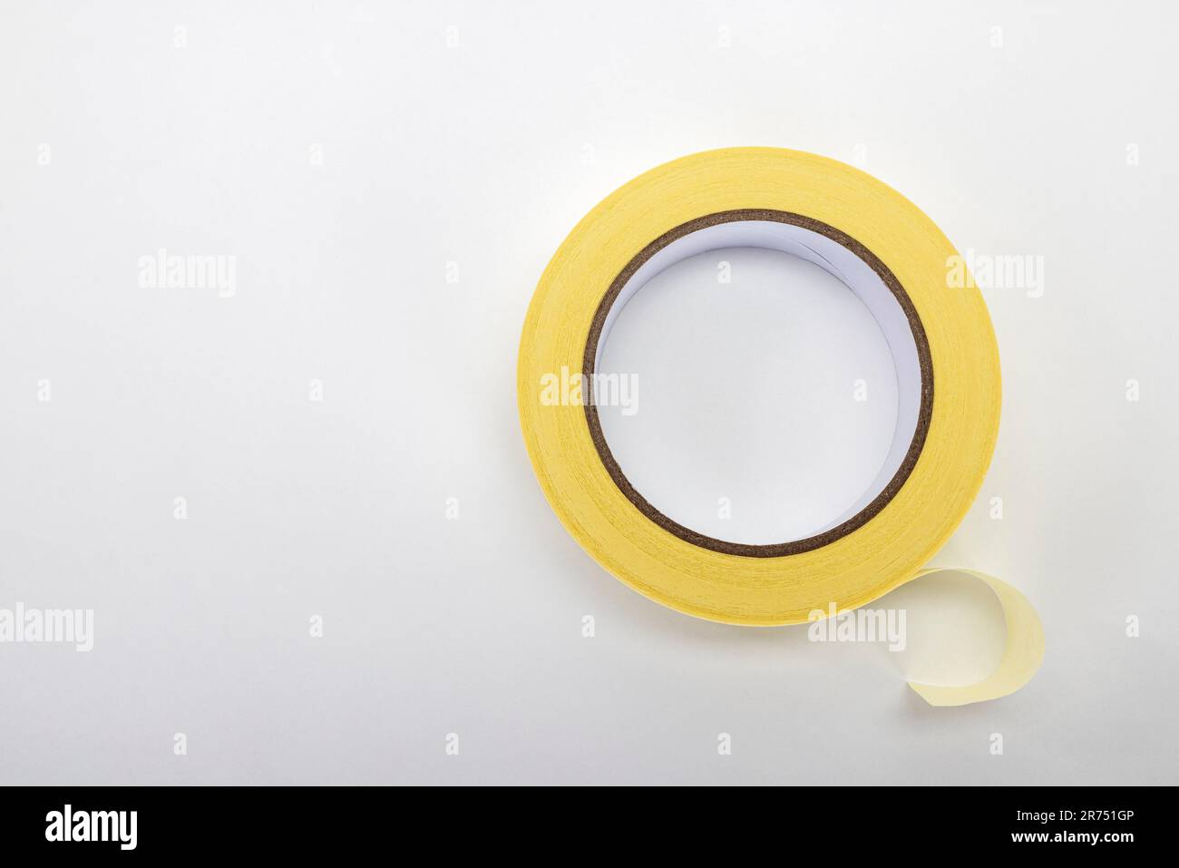 Un rotolo giallo di nastro di mascheratura, nastro di mascheratura per pittori, fondo bianco, Foto Stock