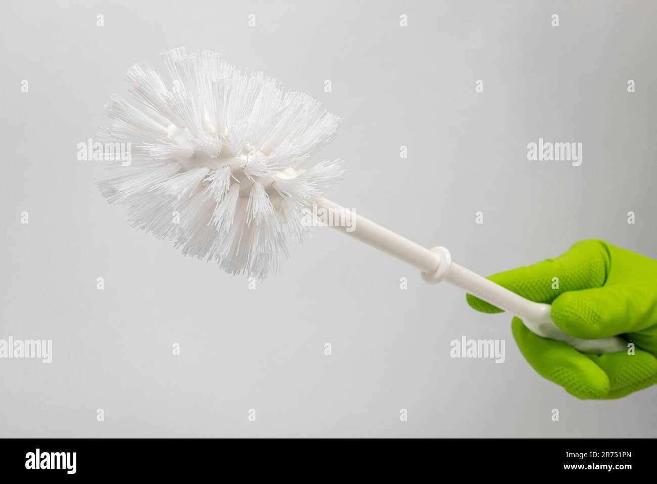 Spazzola per gabinetto bianca, guanto di protezione verde, fondo bianco, Foto Stock