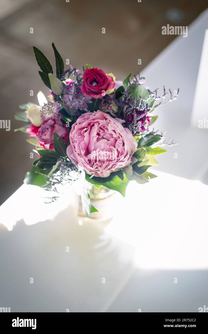 Bouquet di fiori con una peonia rosa come decorazione da tavolo Foto Stock