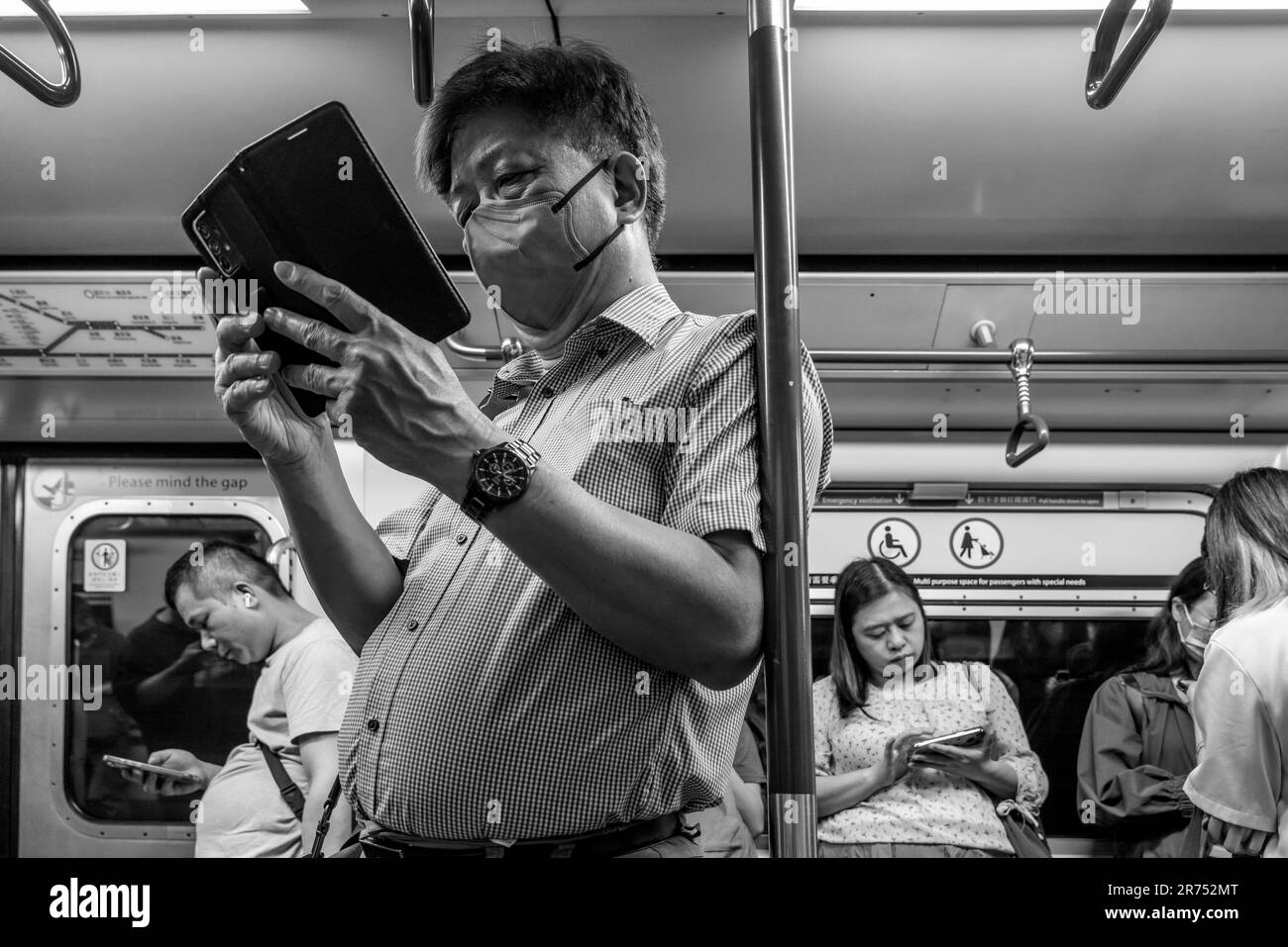 Persone che utilizzano il proprio smartphone su Un treno MTR, Hong Kong, Cina. Foto Stock