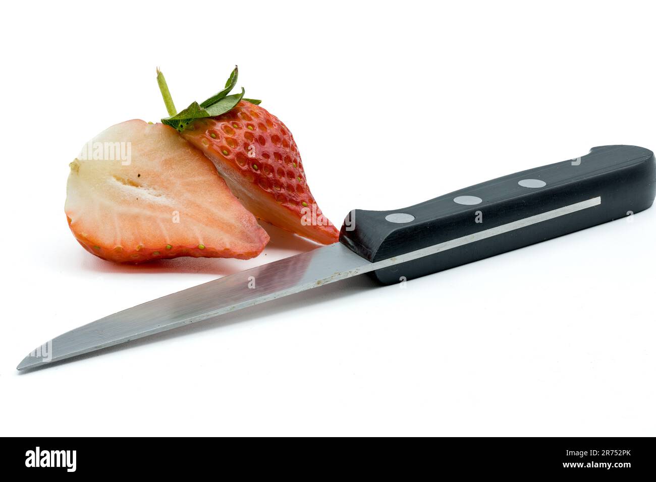 Un coltello con due metà di una fragola affettata su fondo bianco. Foto Stock