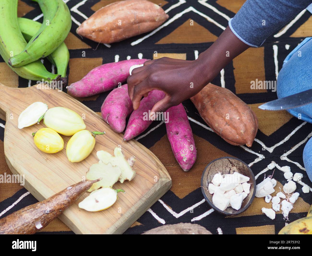 Donna nera che tiene la patata dolce rossa africana, altri ingredienti locali sullo sfondo per la cucina tradizionale ricetta Foto Stock