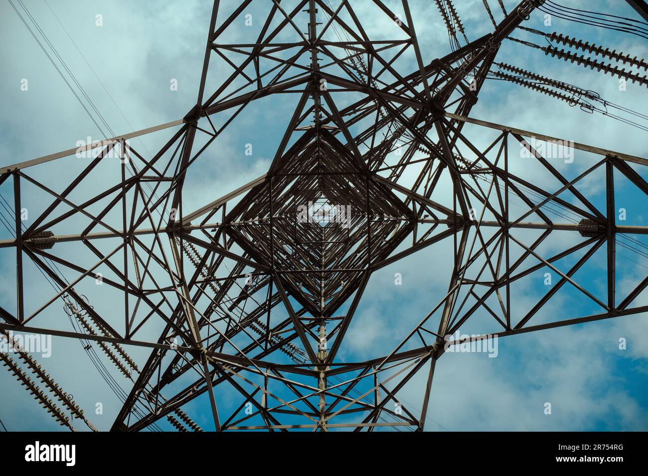 Primo piano di un pilone elettrico illuminato da un sole luminoso sullo sfondo Foto Stock