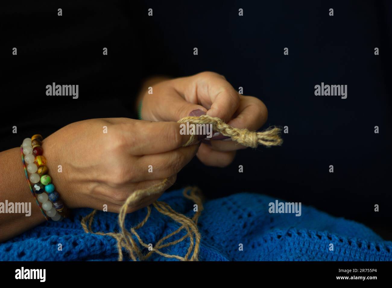 Mani di una donna e filo di iuta e frammento di un disegno a maglia. lavorazione a maglia ecologica naturale, artigianato e hobby, arredamento eco-casa. Foto Stock