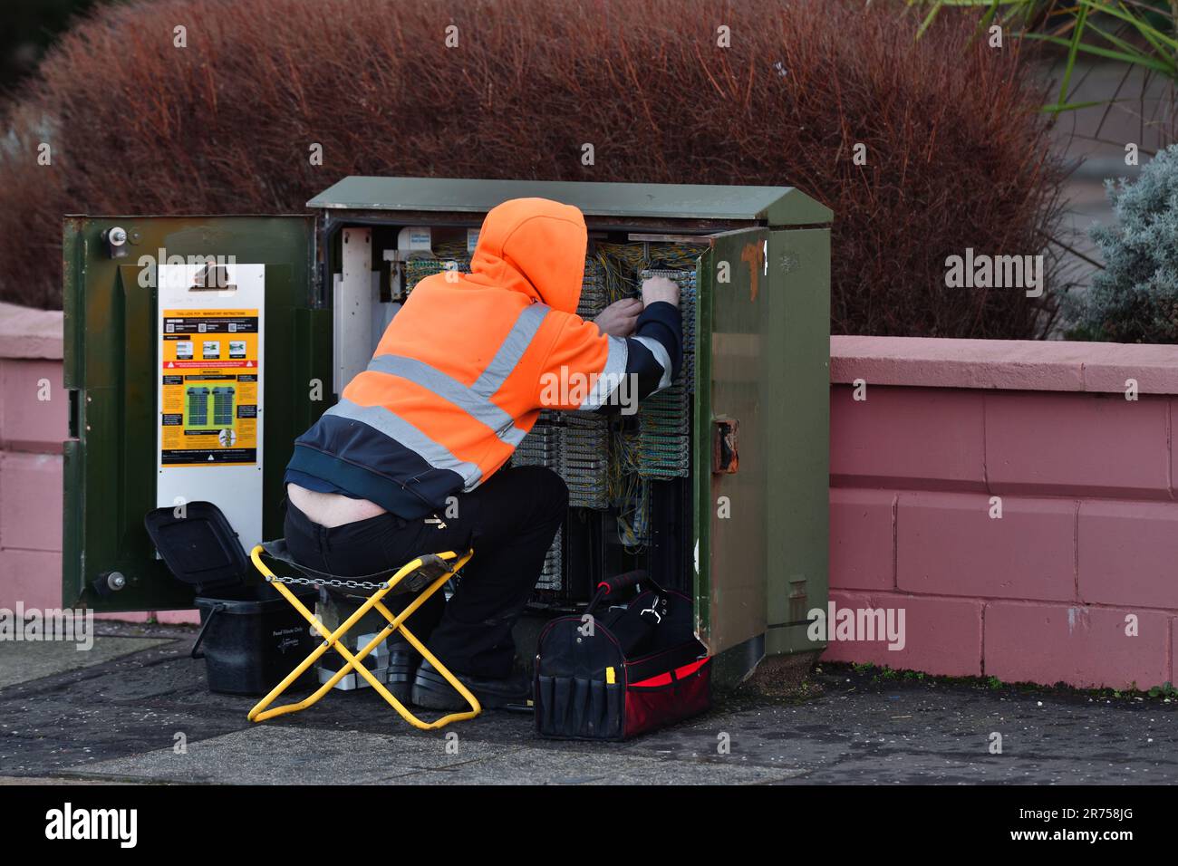 Un ingegnere che esegue riparazioni sul lato strada presso la scatola di derivazione per telecomunicazioni in Scozia Foto Stock