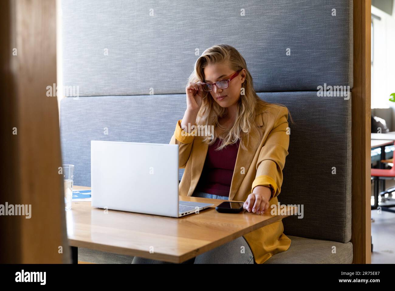 Donna d'affari caucasica casual con occhiali che usa un computer portatile alla scrivania Foto Stock