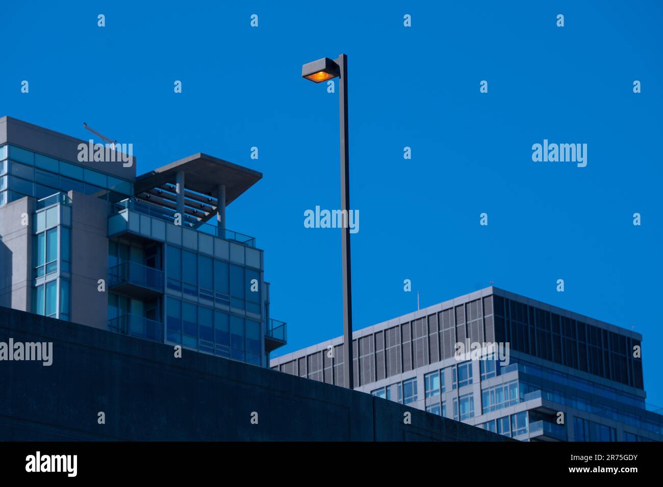Un'inquadratura ad angolo basso di una lampada da strada e moderni edifici di uffici sotto un cielo blu Foto Stock