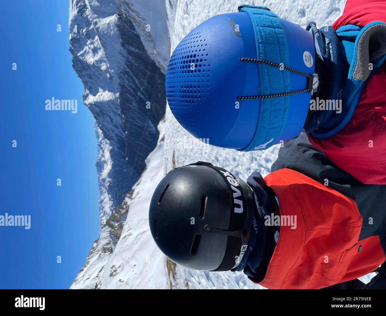 Due bambini con caschi da sci guardano nella stazione sciistica di Samnaun, Ischgl, paesaggio invernale, piste da sci, cielo blu, sole, montagne, natura, attività, Ischgl, Samnaun, Paznauntal, Grigioni, Svizzera Foto Stock