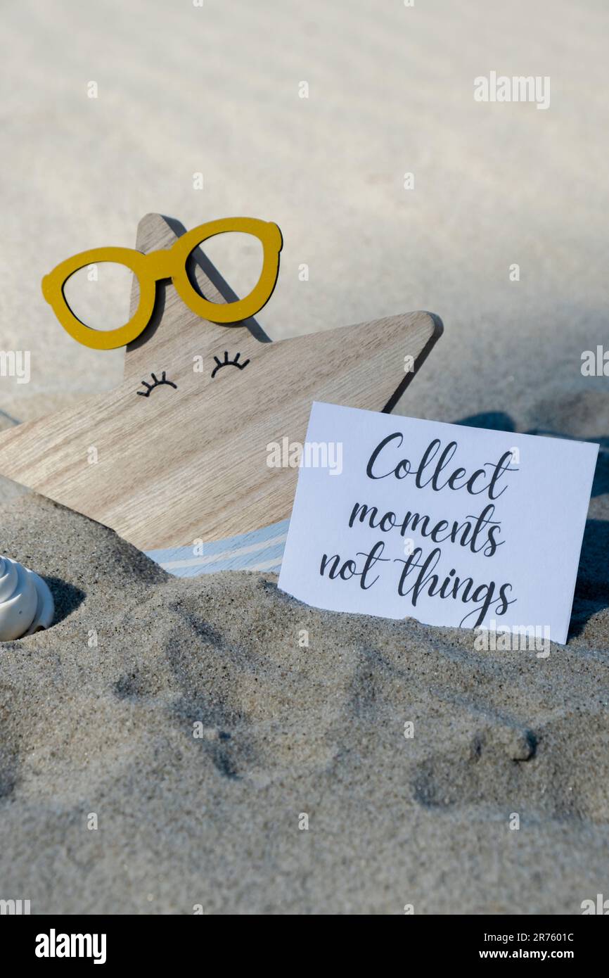 RACCOGLIERE MOMENTI NON COSE testo su carta biglietto di auguri sullo sfondo di divertente stella marina in occhiali decorazione vacanza estate. Spiaggia di sabbia costa sole. Rallentare, godersi il momento, momenti buoni, slow life concetto di vacanza cartolina. Un concetto di viaggio d'affari Foto Stock