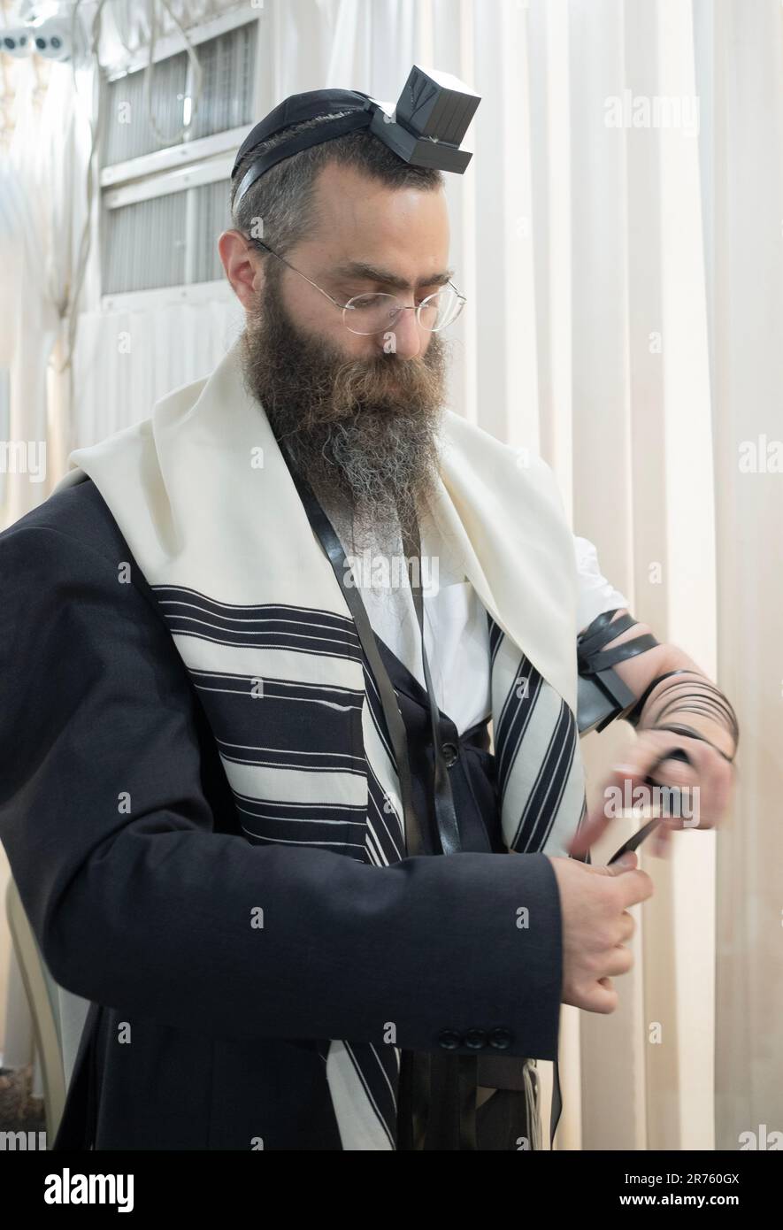 Un rabbino ebraico ortodosso mette su hs tefillin prima dei servizi di mattina. In una sinagoga a Monsey, New Yourk nel 2023. Foto Stock