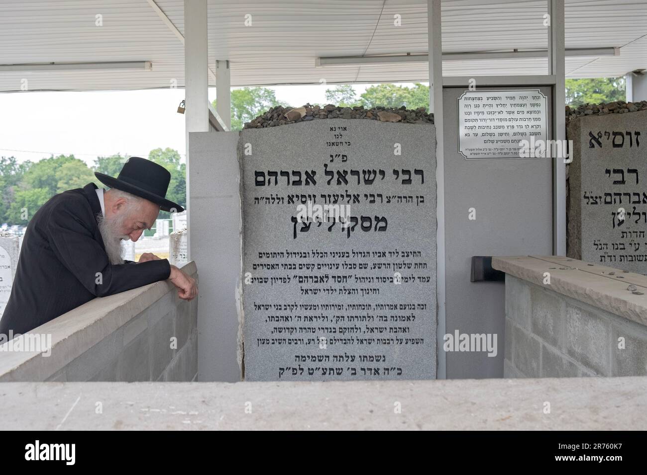 Un anziano ebreo si impegna in fervente preghiera vicino alla lapide di un ex leader della dinastia Skolya Asidica. In un cimitero a Monsey, New York. Foto Stock
