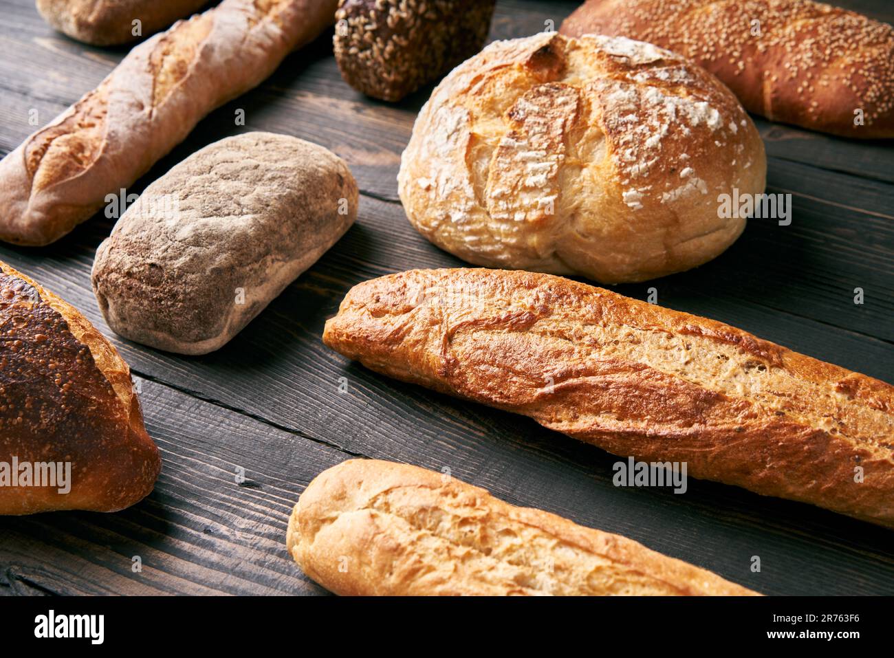 Diversi tipi di pane su sfondo di legno scuro. Panetteria, concetto di cibo delizioso Foto Stock