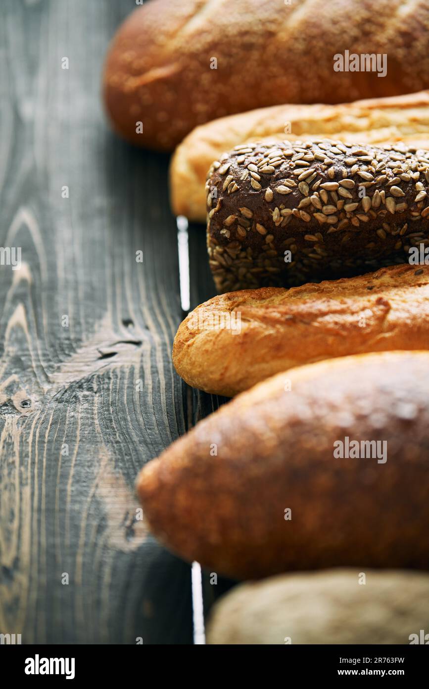 Varie forme di pane fresco su sfondo di legno. Mangiare sano, cibo, panetteria concetto Foto Stock