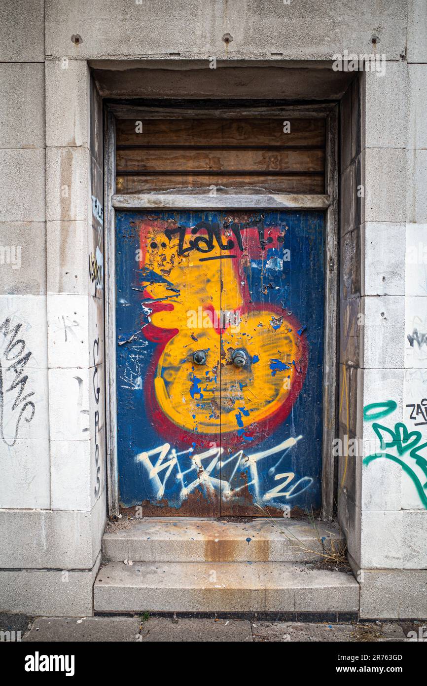 Un'immagine ravvicinata di una porta esterna in un ambiente urbano ricoperto di graffiti. Foto Stock
