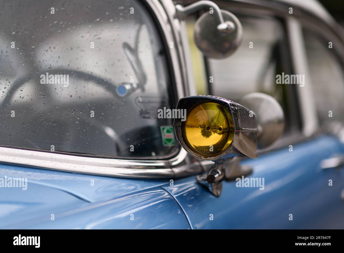 Izmir, Turchia - 3 giugno 2023: Primo piano della luce di segnalazione sullo specchio di una Chevrolet blu cielo 1954, decorata con gocce di pioggia Foto Stock