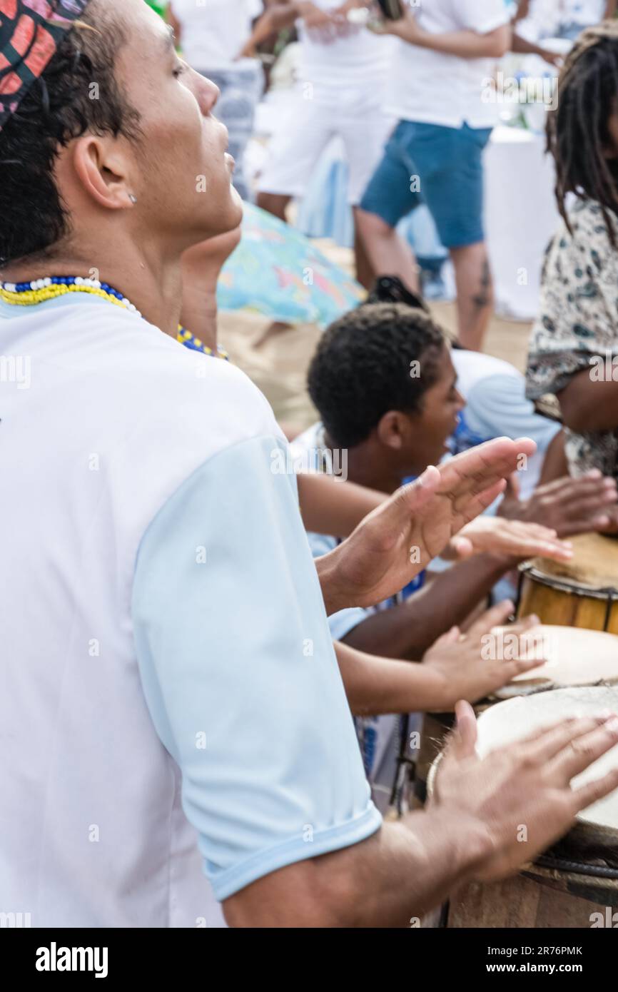 Una scena vibrante e gioiosa di persone di tutte le età che suonano insieme strumenti musicali su una spiaggia soleggiata Foto Stock