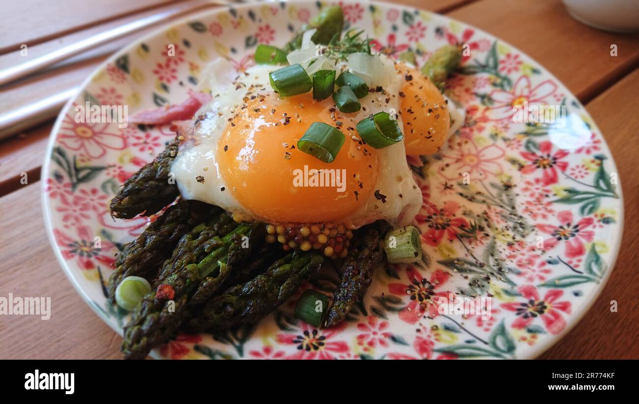 Asparagi verdi alla griglia con uova fritte e erba cipollina. Colazione fresca su piatto. Foto Stock