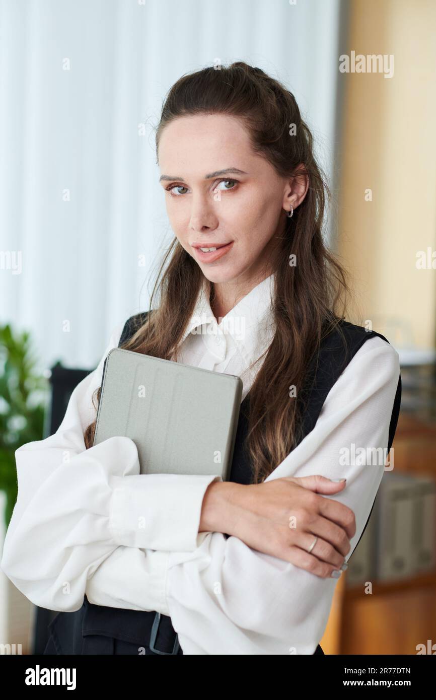 Immagine verticale di un giovane manager con un tablet che sorride davanti alla fotocamera in ufficio Foto Stock