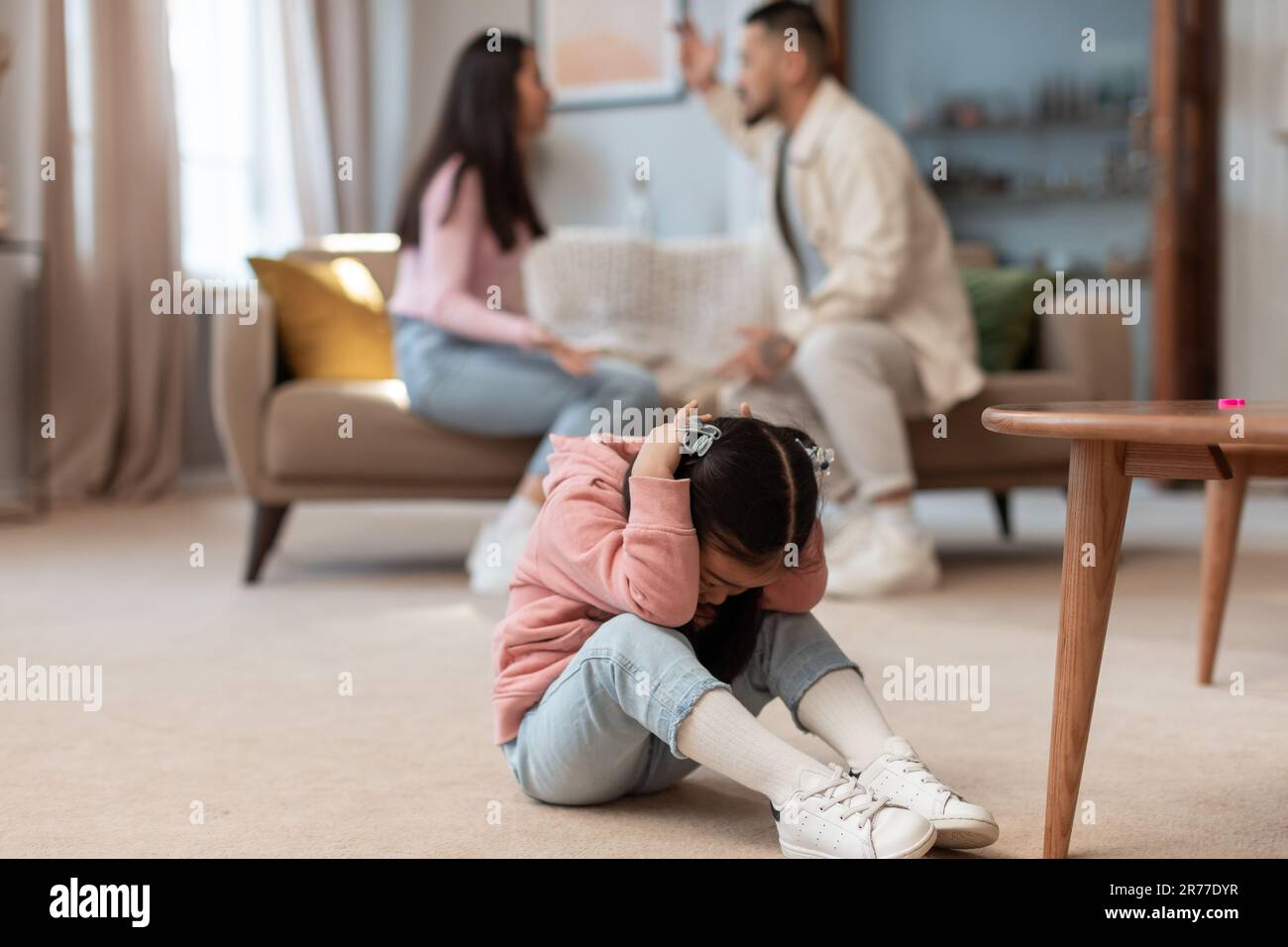 Il bambino asiatico copre le orecchie mentre i genitori arrabbiati combattono a casa Foto Stock