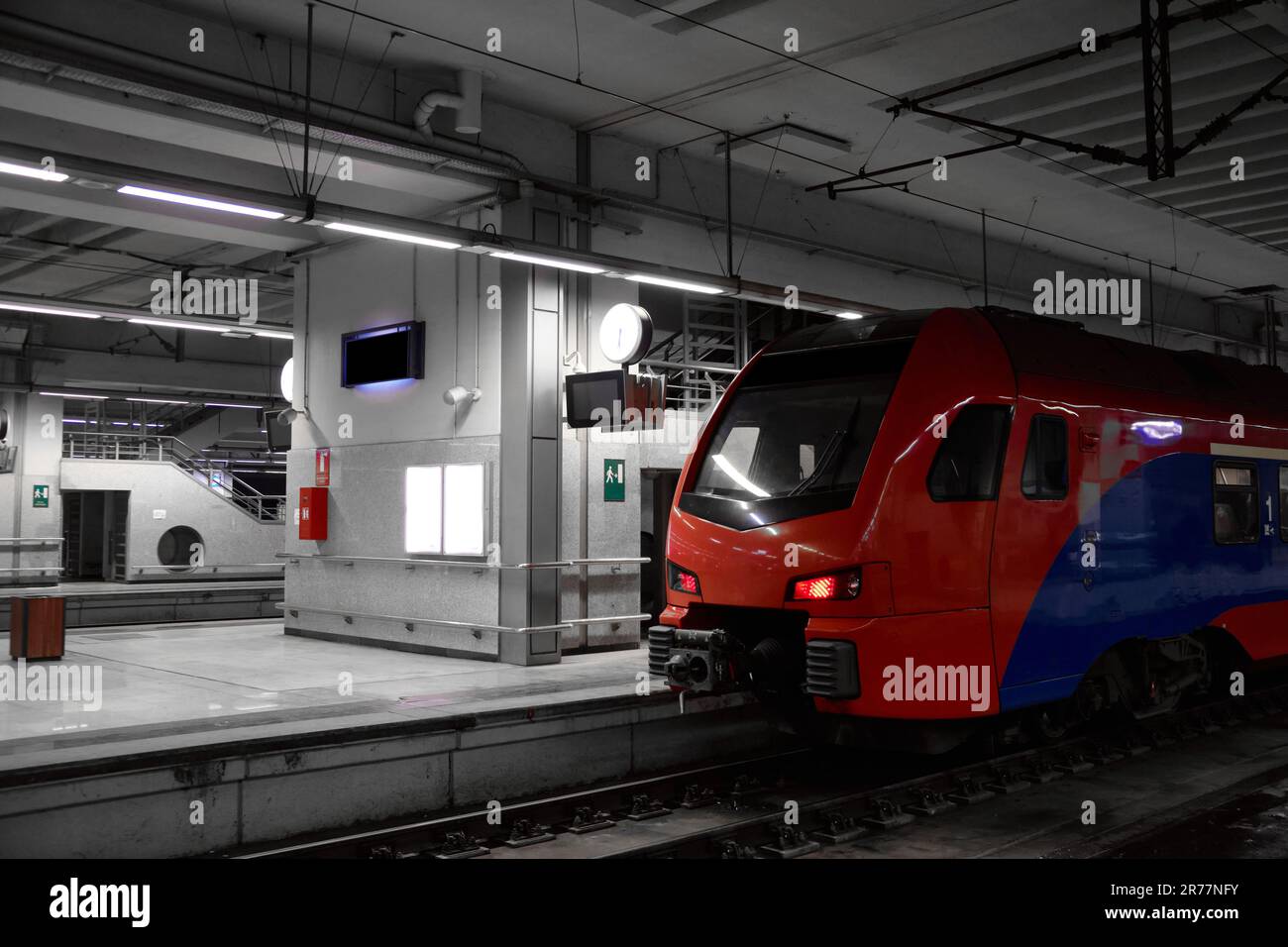 Treno passeggeri rosso e blu al binario della stazione ferroviaria. Il treno per pendolari è pronto per la partenza dalla stazione ferroviaria Foto Stock