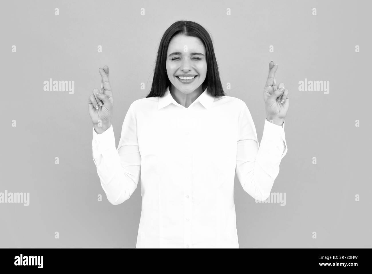 Ritratto di donna divertente con le dita incrociate per buona fortuna, sfondo isolato. Headshot di donna felice attraversa le dita con espressione positiva, beli Foto Stock