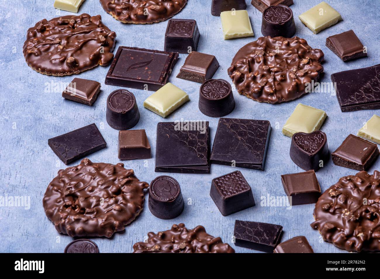 Varietà di prodotti di cioccolato fotografati in studio su sfondo grigio chiaro con texture bianca. Cioccolato fondente, cioccolato al latte, cioccolato bianco, c Foto Stock