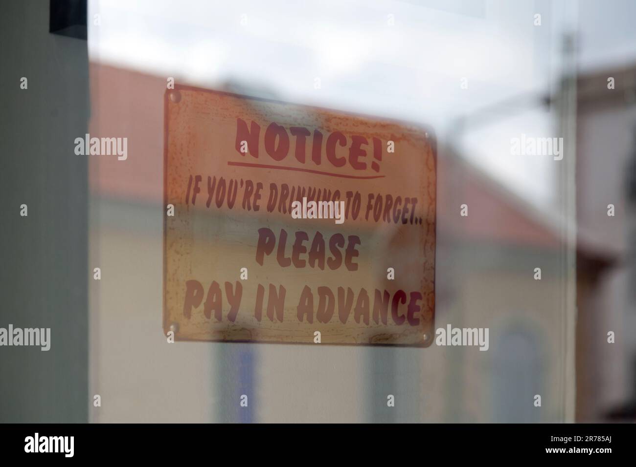 Cartello all'ingresso di un bar che dice: 'Avviso! Se si beve per dimenticare, si prega di pagare in anticipo". Foto Stock