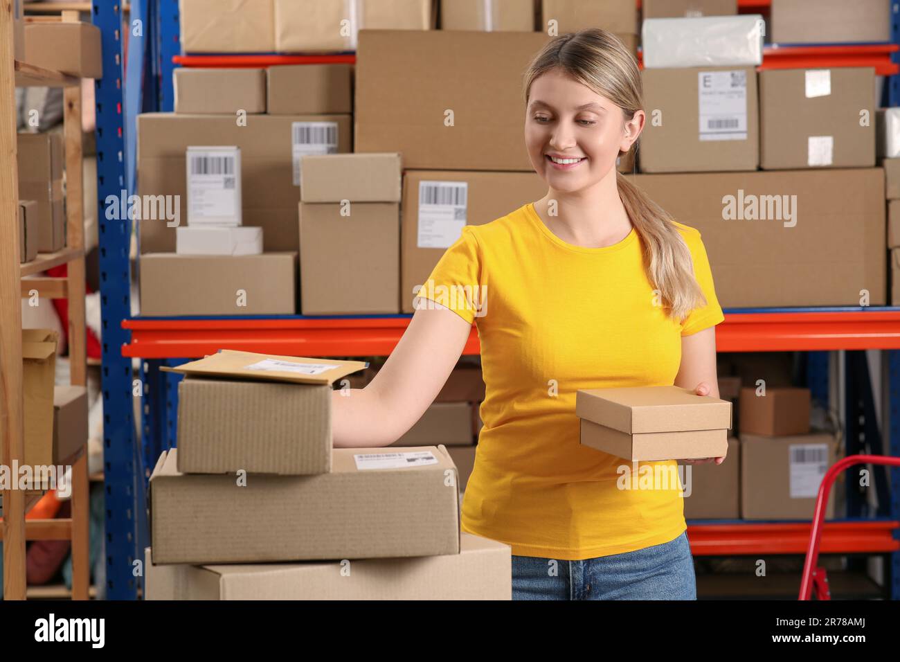 Addetto all'ufficio postale con pacchi vicino al rack interno Foto Stock