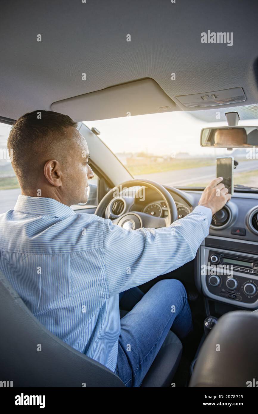Conducente che utilizza un telefono cellulare all'interno della sua auto. Foto Stock