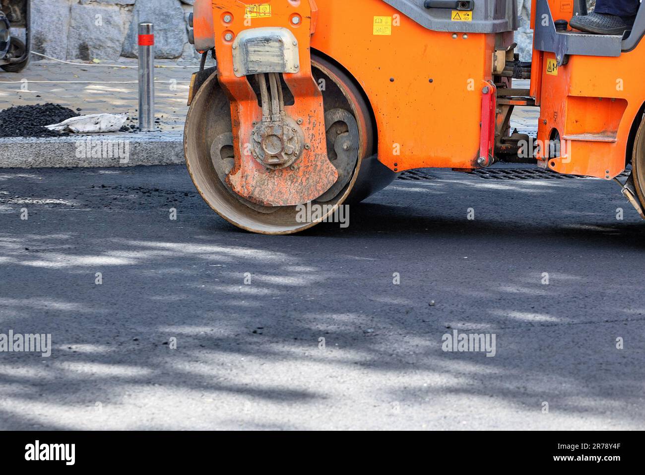 Un frammento del lavoro di un rullo stradale per la compattazione dell'asfalto in una giornata estiva. Foto Stock