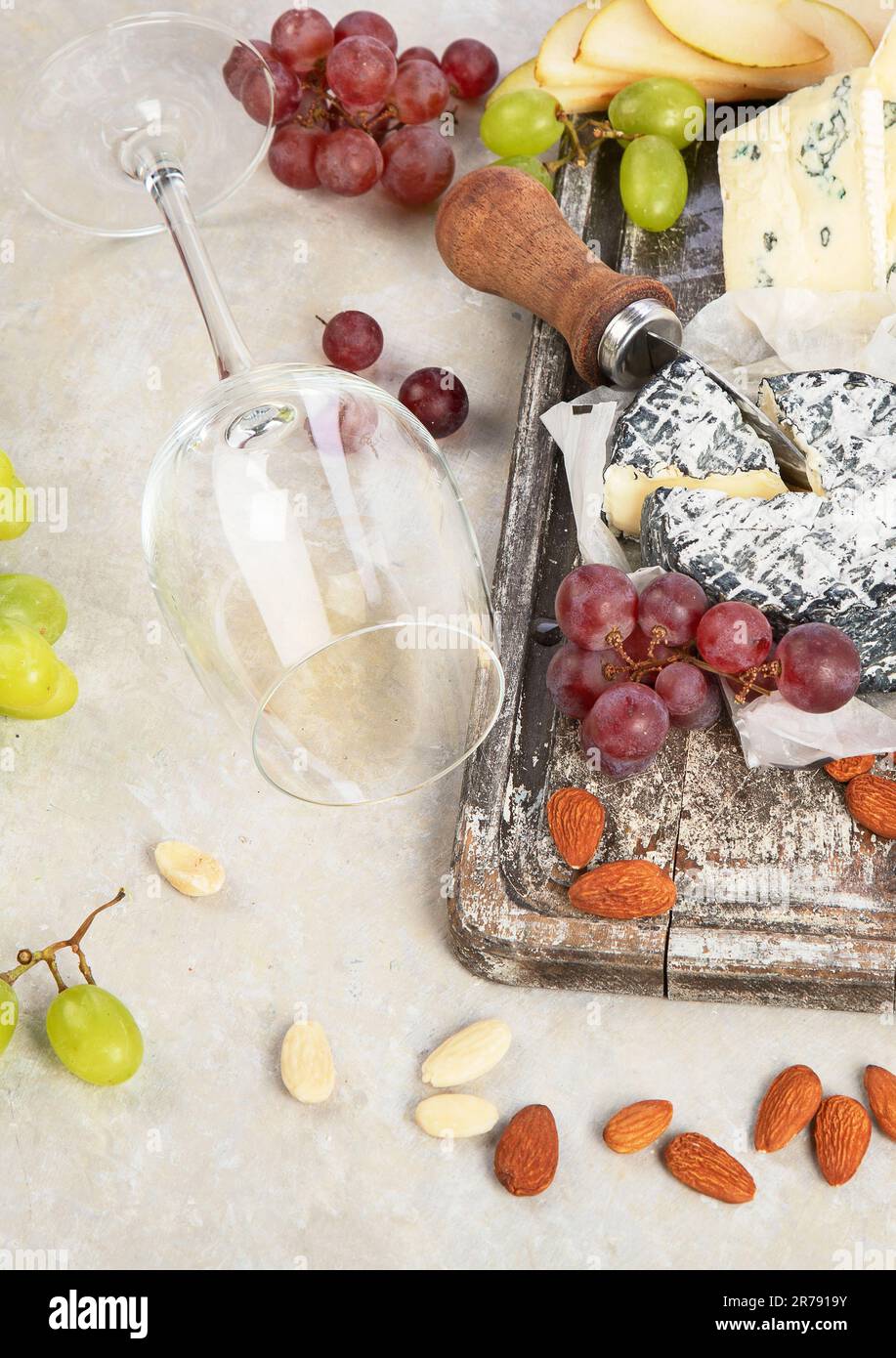 Vino rosa e rosso servito con formaggi, noci, uva e bicchieri di vino. Deliziosi spuntini enogastronomici assortiti serviti a bordo. Piatto poggiato su un bac bianco Foto Stock