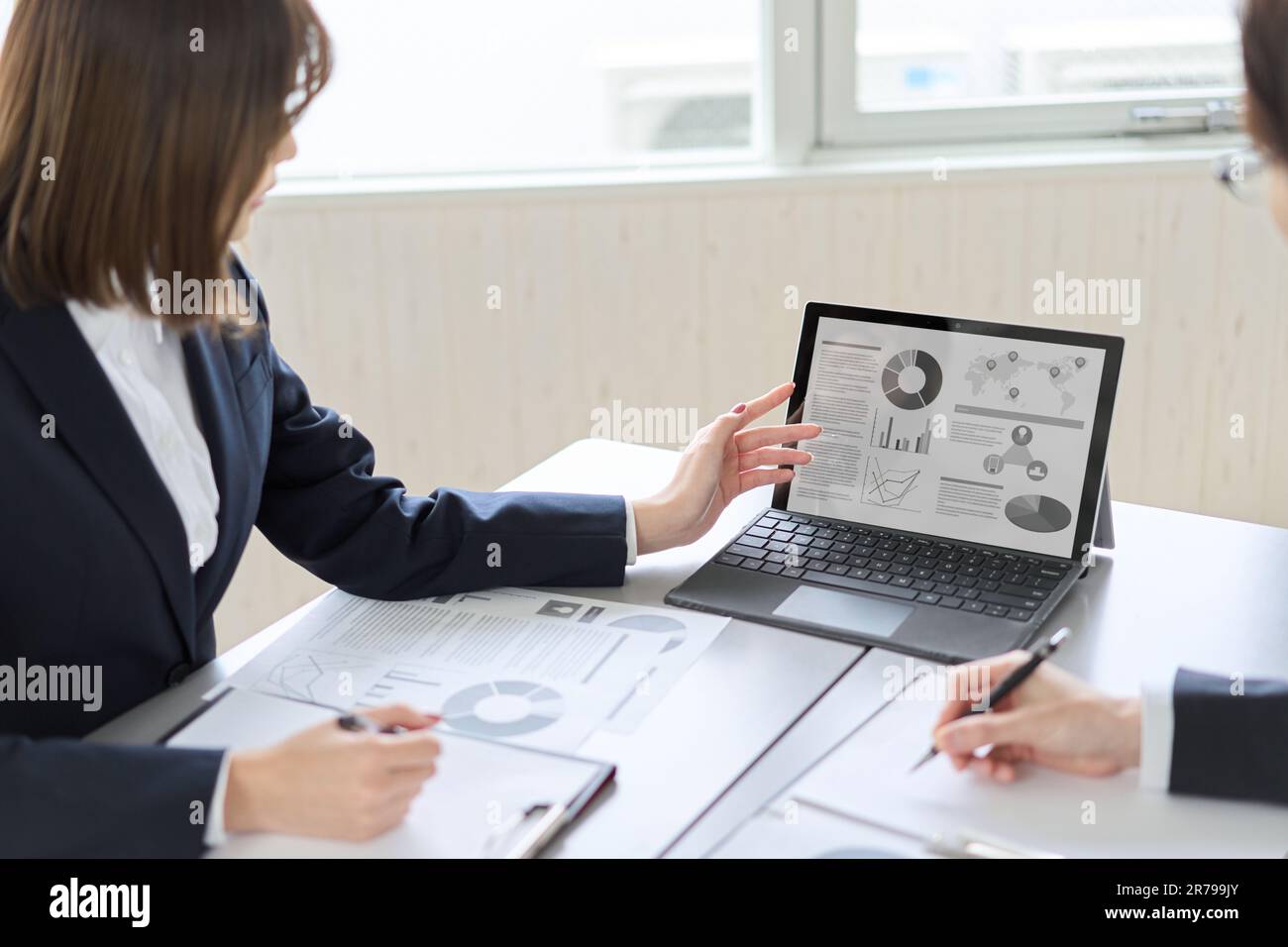 Donna asiatica d'affari che mostra e spiega un computer Foto Stock