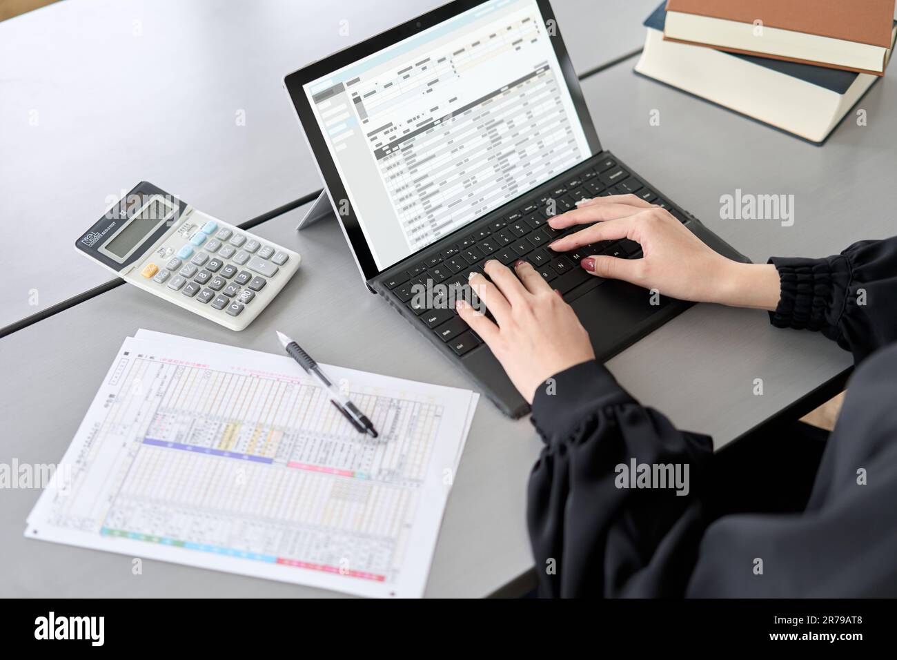 Donna asiatica che inserisce voci di giornale nel software di contabilità Foto Stock