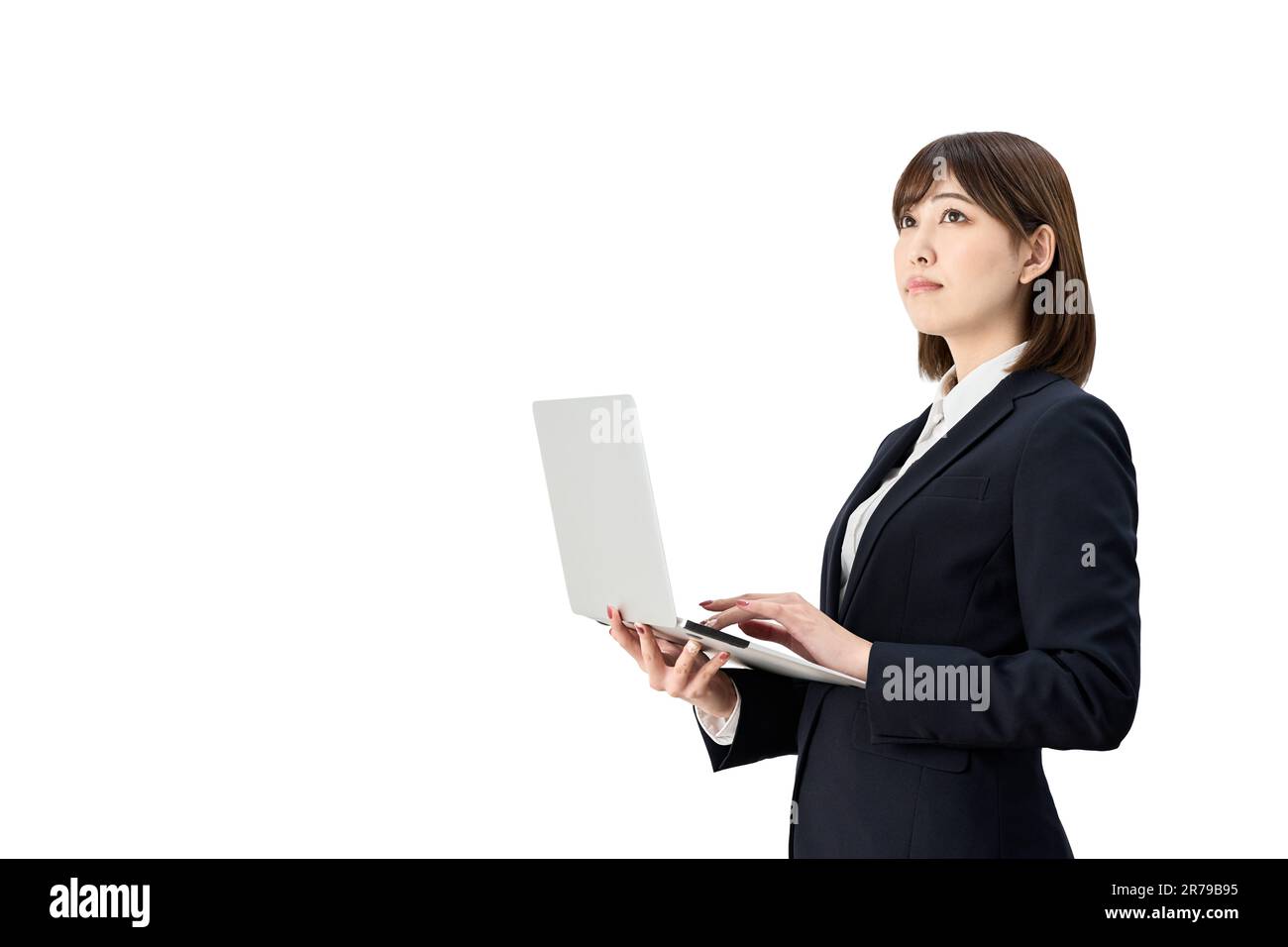 Donna asiatica d'affari che guarda in alto mentre lavora sul suo notebook Foto Stock