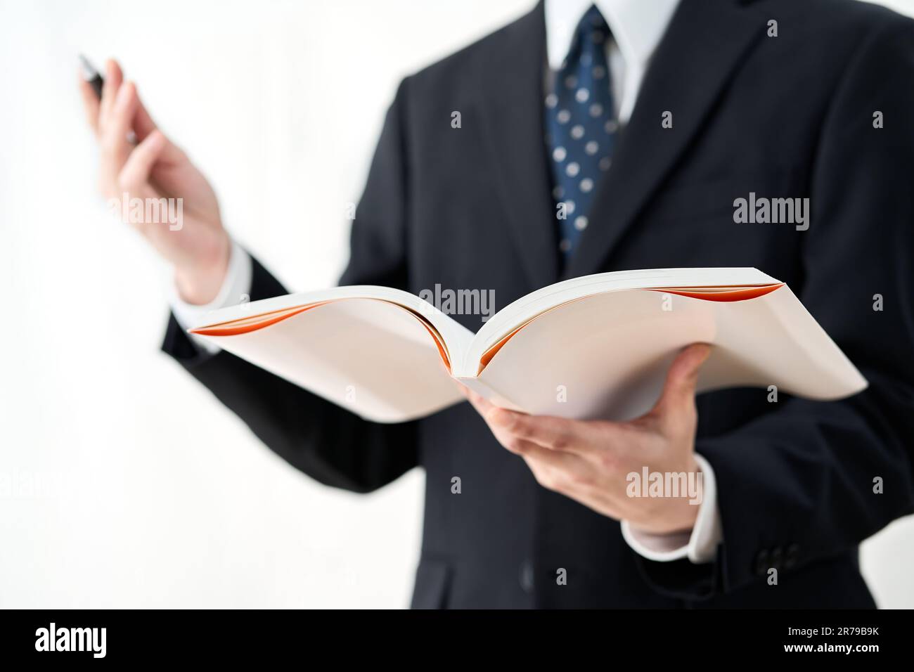 Un insegnante di scuola che spiega con un libro di riferimento Foto Stock