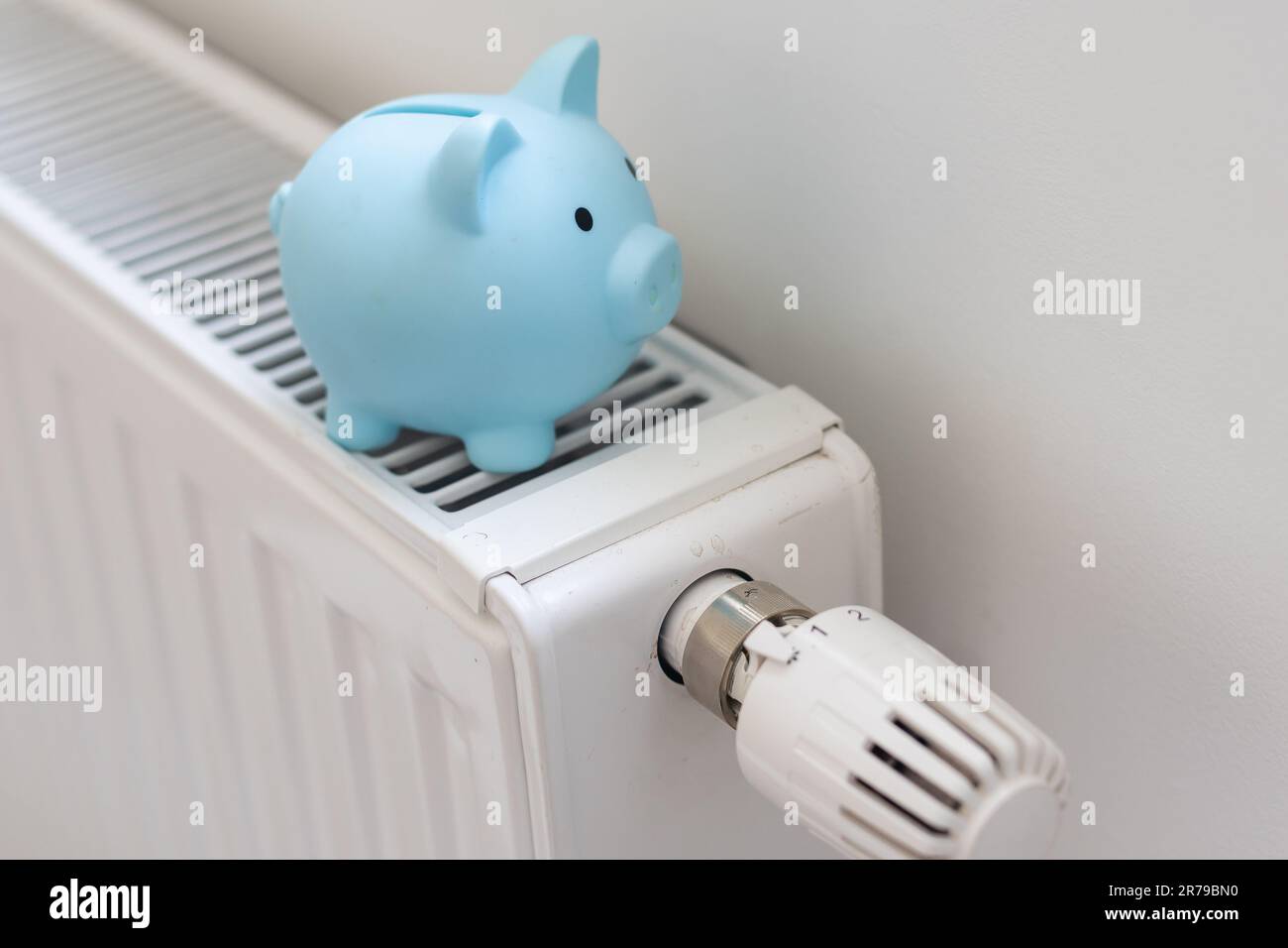 Porcellino piggy banca e dollari fatture su un radiatore al chiuso-up. Concetto di riscaldamento. Foto Stock