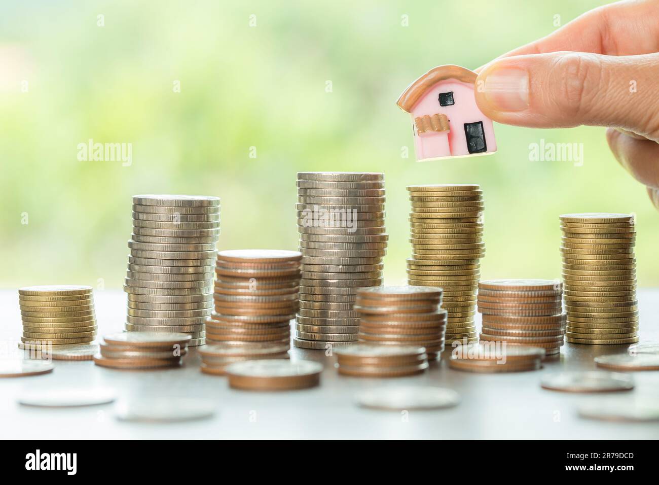 Tenere a mano casa con monete da soldi per risparmiare per residenziale. piano finanziario in contanti per prestiti o ipoteche e investimenti con banca. Concetto per casa in Foto Stock